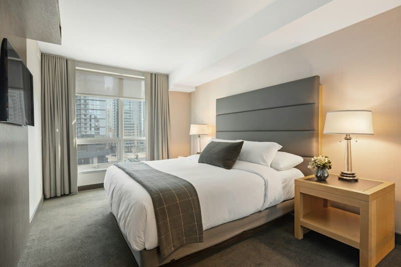 Bright hotel room with a made-up king bed and city view