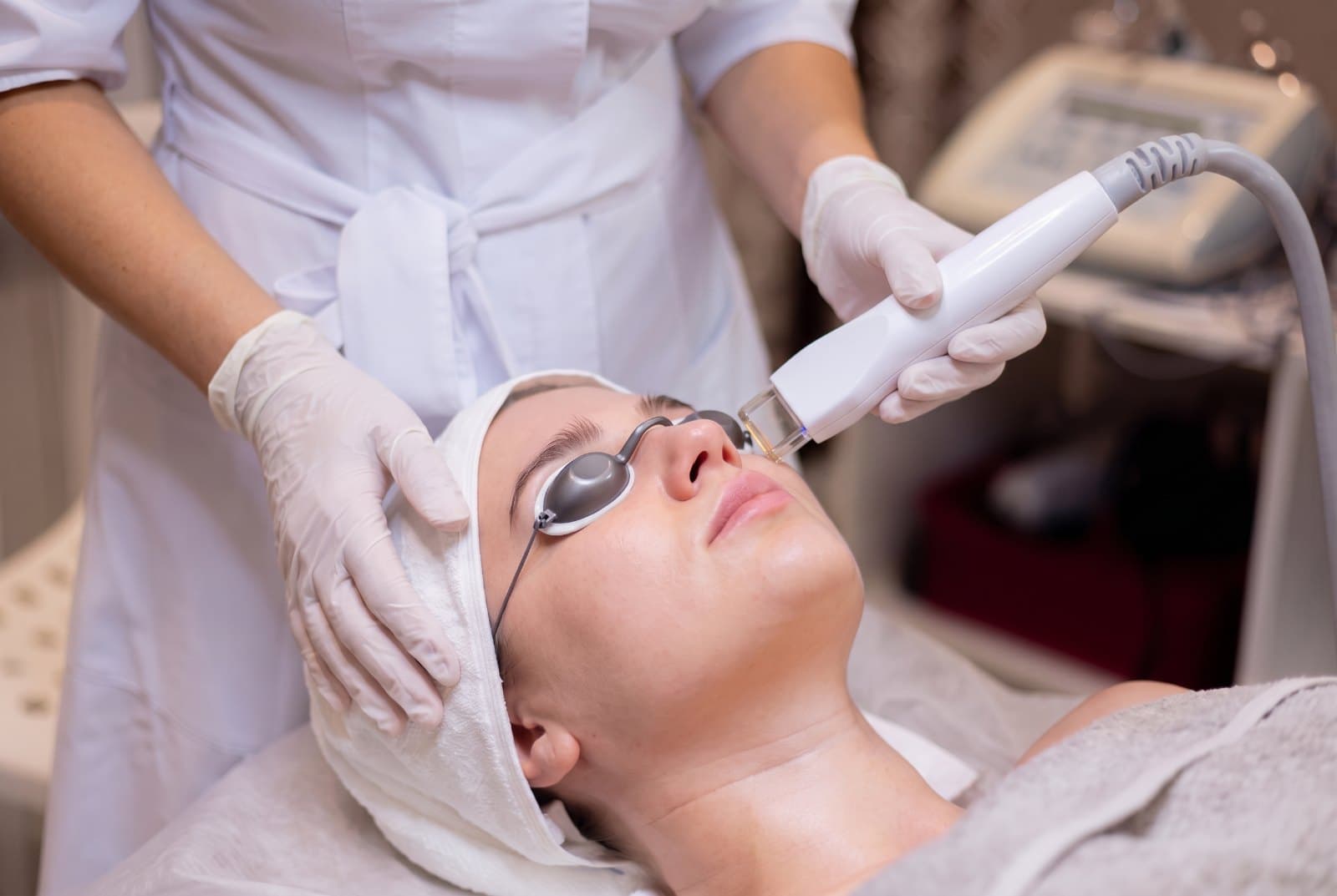 Intense pulsed light handpiece on a patient's cheekbone just under her eye, both eyes shielded