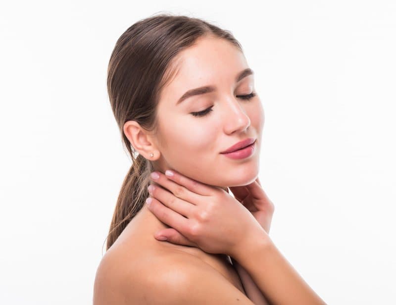 Woman with smooth, even skin touching her neck